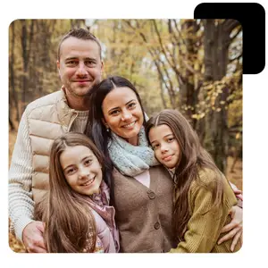 A family of four smiling for a photo in a forest