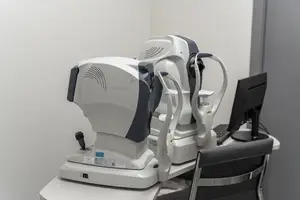 An eye examination machine with a monitor on a desk in a medical room