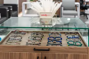 An optician's shop with a wooden cabinet displaying eyeglasses and an Etnia Barcelona sign.