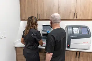 Two people in a room looking at a Visionix machine