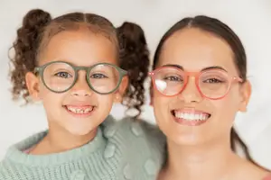 Close up of a mother and daughter wearing glasses and smiling at the camera