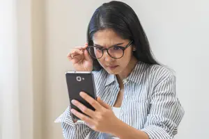 Woman looking at her phone with glasses on her head.
