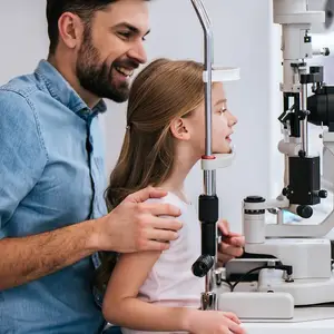 A man and a girl are looking into an eye examination machine