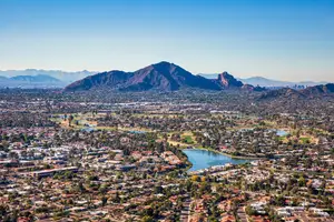 Aerial view of a city with many buildings, houses, and a lake with mountains in the background