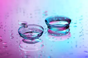 two contact lenses sitting on a surface with droplets of water around them