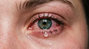 A close up of a woman's eye with a teardrop in it