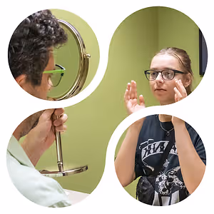 A person is looking at their face in a mirror while another person holds the mirror. The other person is looking at their face and holding their hands together. A girl with a backpack is also looking at their face. The room is painted green. The image is circular and has a white border.