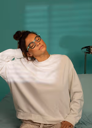 woman with glasses lying on bed