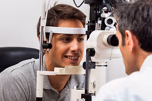 Man in gray shirt getting his eyes examined by a doctor wearing a white coat