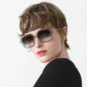 A woman with short hair wearing sunglasses and a black top
