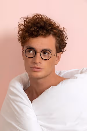 A man wearing glasses and a white blanket around his neck.