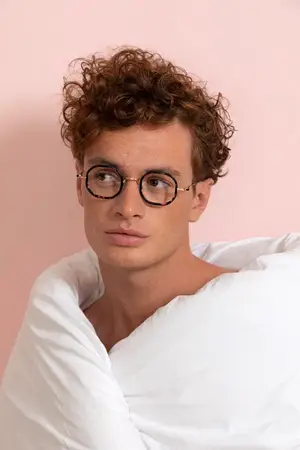 A man wearing glasses and a white blanket around his neck.