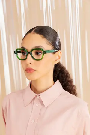 Woman wearing pink shirt and green rectangular glasses