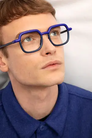 man wearing purple glasses with a buttoned blue shirt