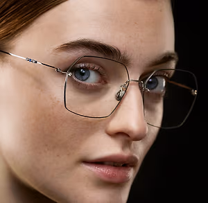 A woman with blue eyes wearing a pair of glasses with a metallic frame