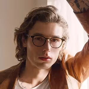 Man wearing glasses and a brown jacket posing for a picture