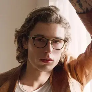 Man wearing glasses and a brown jacket posing for a picture