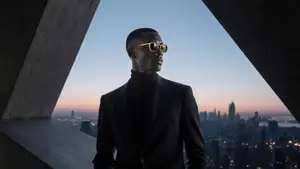 A man standing on the rooftop of a building at sunset with a cityscape in the background