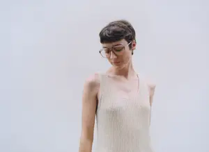 A woman with short hair and glasses is looking down at something in front of her
