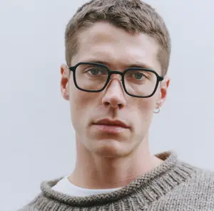 A man wearing glasses and a sweater posing for a photograph