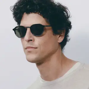 A man with curly hair wearing sunglasses and a white shirt