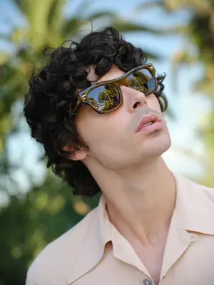 Man with curly hair and sunglasses looking up