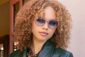 A woman with curly hair wearing sunglasses and a green jacket