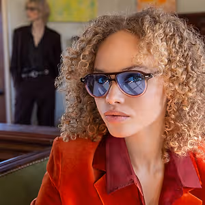 Woman with curly hair wearing sunglasses and a red jacket