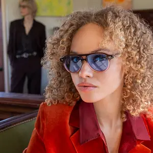 Woman with curly hair wearing sunglasses and a red jacket