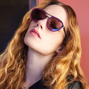 Woman with long wavy blonde hair wearing black leather jacket and purple framed sunglasses