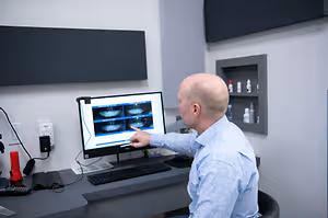 A man is showing an image on a computer monitor in an office room