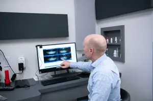 A man is showing an image on a computer monitor in an office room