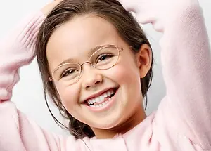 A smiling girl with glasses wearing a pink sweater posing for a photo