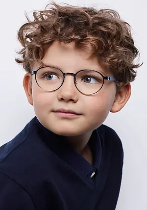 Close-up of a boy with curly hair and blue eyes wearing glasses and a blue polo shirt