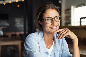 Woman in blue shirt smiling in a coffee shop