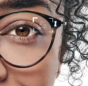 Close up of woman's eye wearing glasses with a camera icon overlaid on the eye