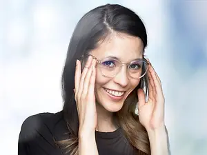 A woman smiling and adjusting her glasses