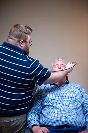 Optometrist examining an older man's eyes with a handheld instrument