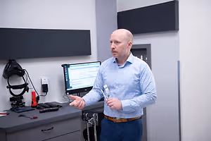 Optometrist standing beside an eye examination workstation and discussing equipment