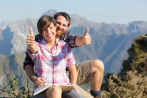 Smiling couple giving thumbs up on a mountain overlook