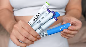 Person holding several GLP-1 medication injection pens