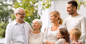 A family is standing in front of a house, smiling, and looking happy.