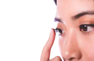 Close up of a woman's face with a finger on her eyelid.