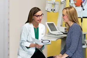 Two women smiling and talking in a doctor's office