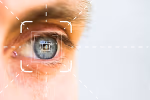 A close-up of a man's eye with a white square on it and a heartbeat line in the corner