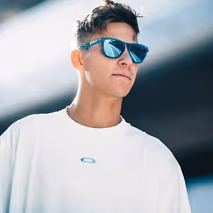 A man wearing white T-shirt and blue sunglasses is looking towards the right. He seems to be posing for a photo.