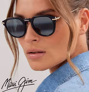 A woman with blonde hair wearing black sunglasses with a Maui Jim signature on a denim jacket.