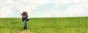 A young boy doing a cartwheel in a grassy field under a cloudy sky