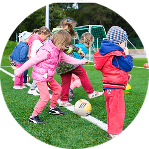 A group of children are playing with soccer balls on a grassy field.