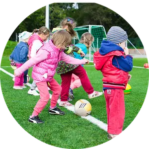 A group of children are playing with soccer balls on a grassy field.